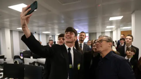 PA Media Sir Keir takes a selfie with teenagers in school uniform 