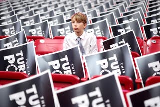 A young attendee sits in the stands ahead of the memorial service for political activist Charlie Kirk