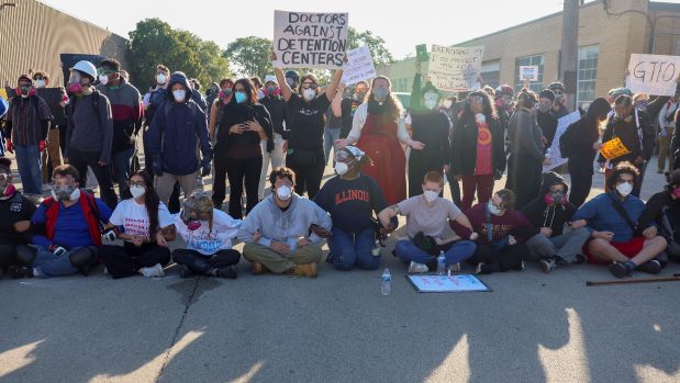 Protesters lock arms and block Harvard Street while federal agents stand guard at a gate leading to the U.S. Immigration and Customs Enforcement facility on Sept. 26, 2025, in Broadview. (Stacey Wescott/Chicago Tribune)